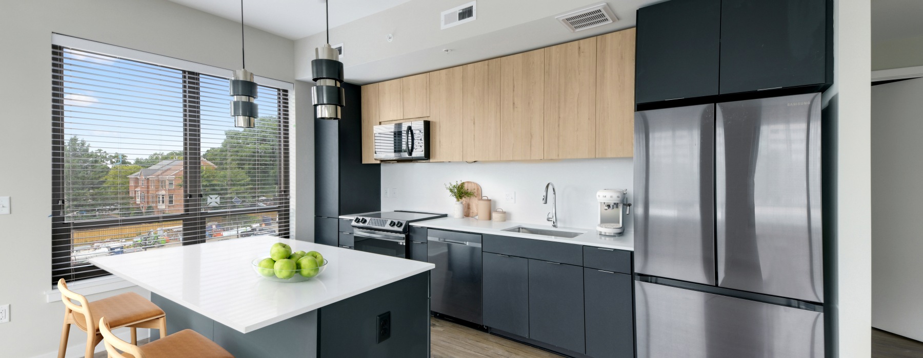 Model kitchen at our apartments for rent in Arlington, VA, featuring wood grain floor paneling and a kitchen island.