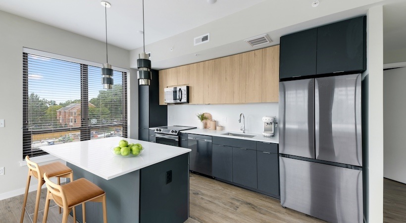 Model kitchen at our apartments for rent in Arlington, VA, featuring wood grain floor paneling and a kitchen island.