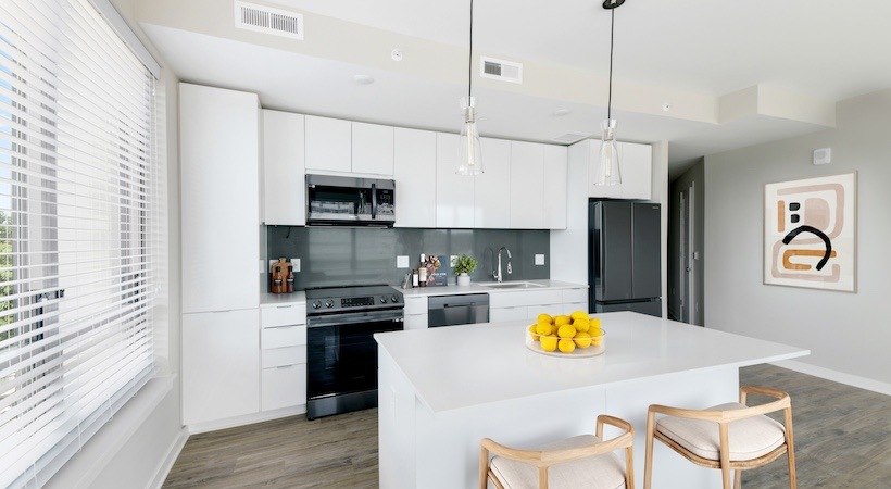 Model kitchen at our apartments for rent in Arlington, VA, featuring wood grain floor paneling and a kitchen island.