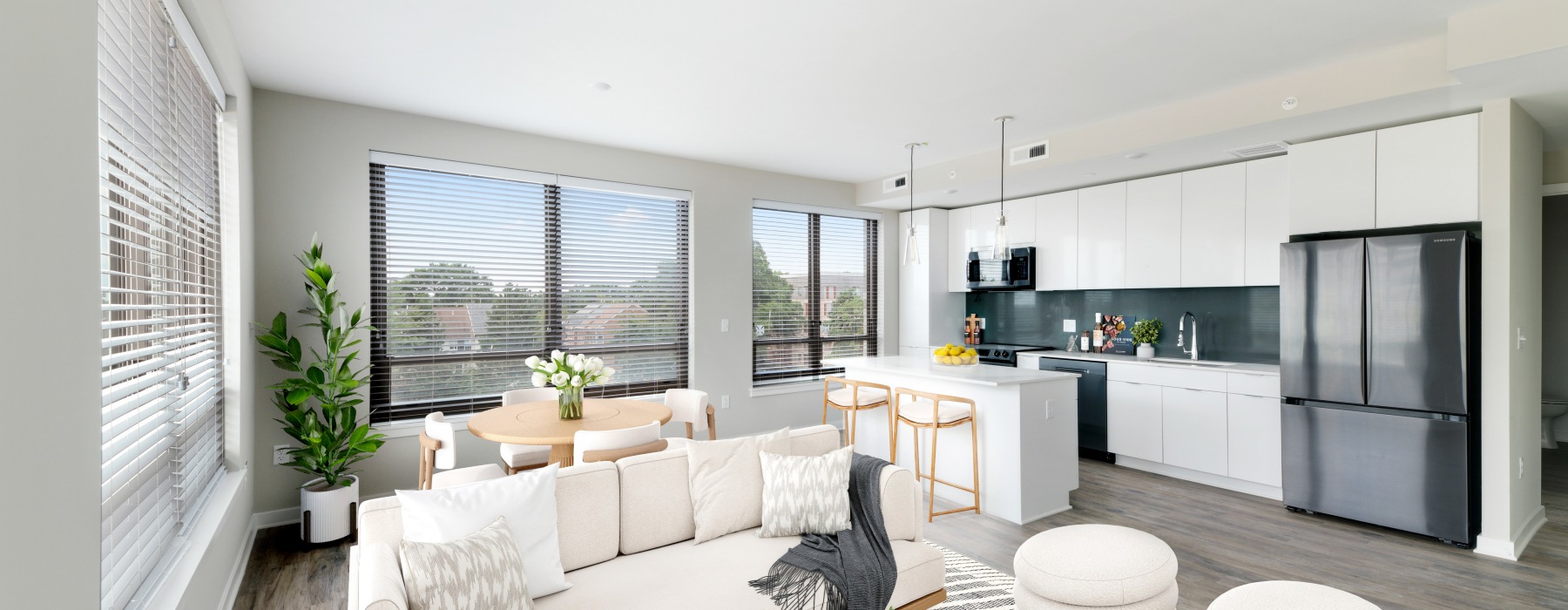 Model living room at our apartments in Ballston, featuring wood grain floor paneling and a view of the kitchen.