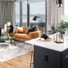 Model living room at our apartments in Ballston, featuring wood grain floor paneling and a view of the kitchen.